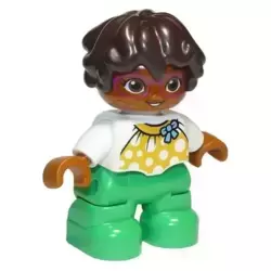 Duplo Figure Lego Ville, Child Girl, Bright Green Legs, White Top with Yellow Pattern and Blue Bow, Dark Brown Wavy Hair, Magenta Glasses (6295446)
